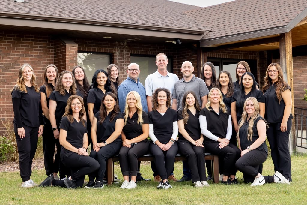 The Ashley Valley Family Dental team standing in front of their brick office